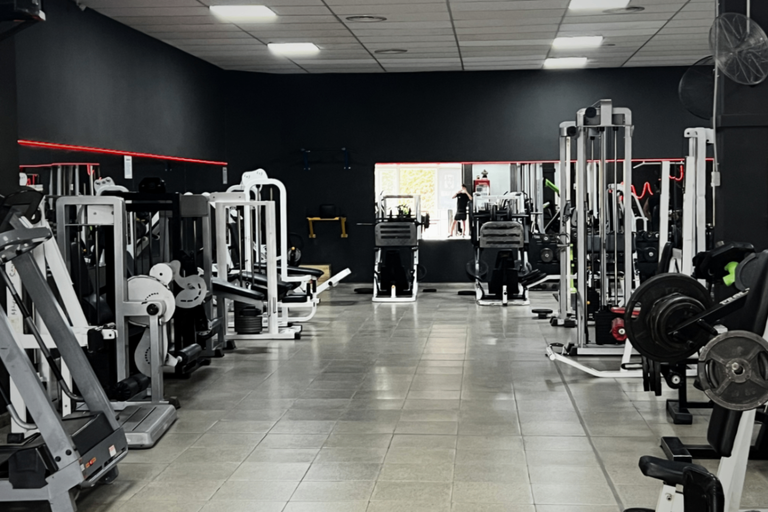 Pasillo central con máquinas de musculación y espejos en Mutant Gym